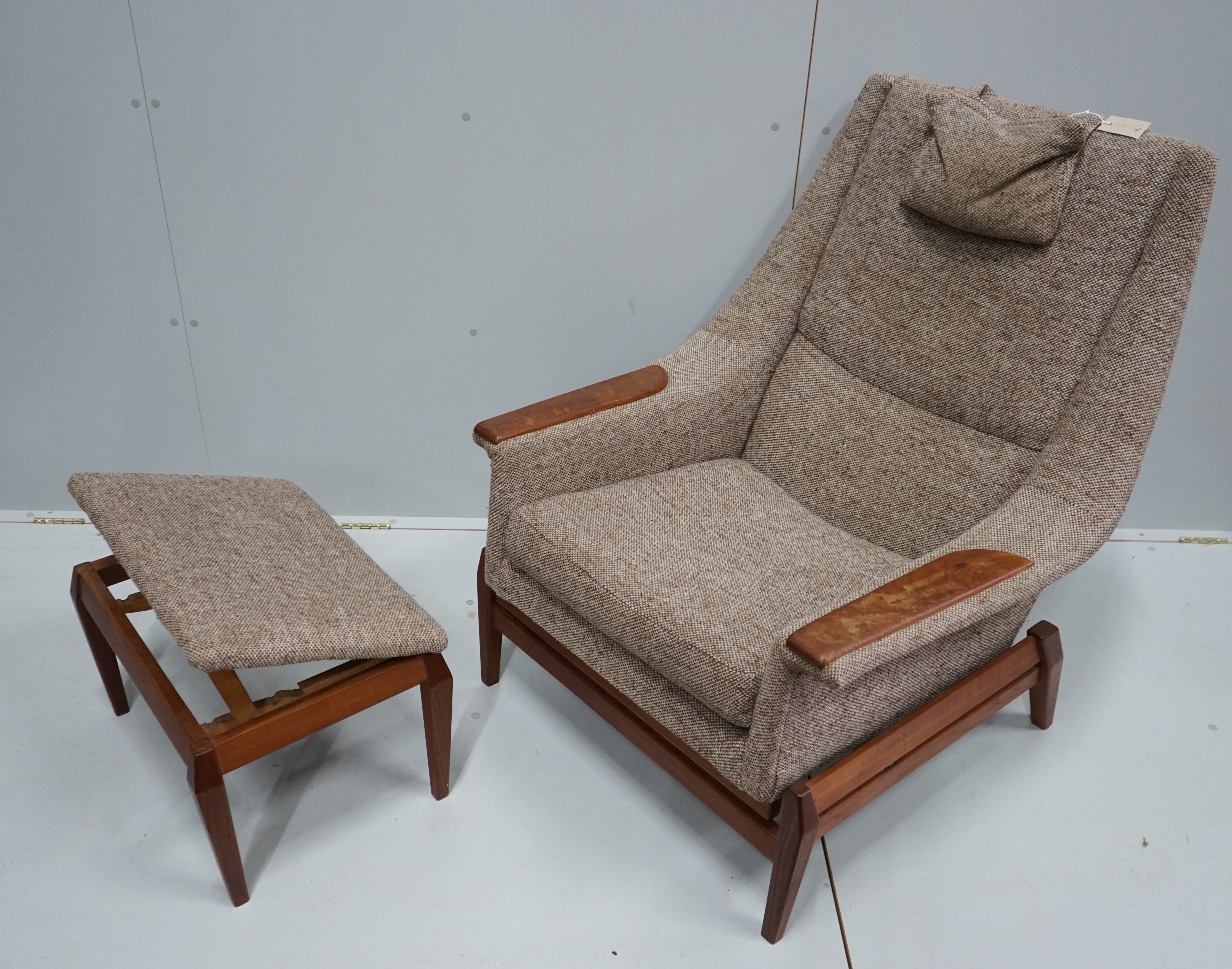 In the manner of Kofod Larsen, a mid century upholstered teak reclining armchair and adjustable foot stool, chair width 87cm, depth 86cm, height 102cm.